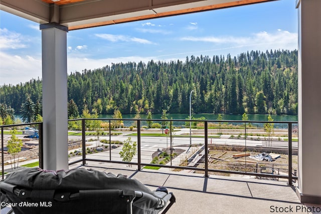 balcony featuring area for grilling, a water view, and a view of trees