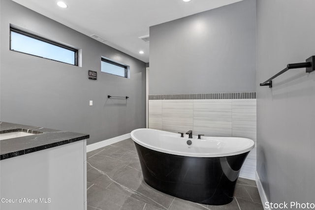 full bathroom featuring recessed lighting, baseboards, a freestanding bath, and vanity