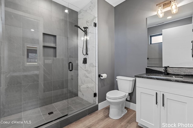 bathroom with baseboards, toilet, wood finished floors, vanity, and a shower stall