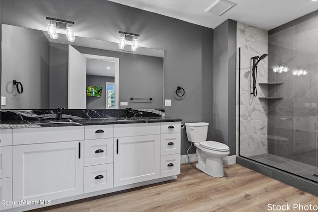 full bathroom featuring visible vents, toilet, a sink, wood finished floors, and tiled shower