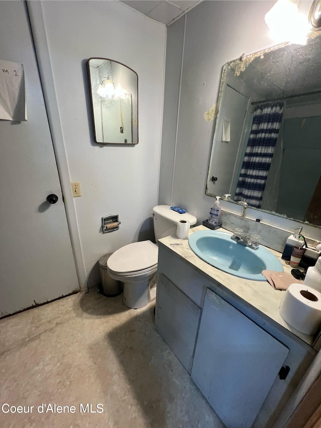 bathroom featuring concrete floors, vanity, and toilet