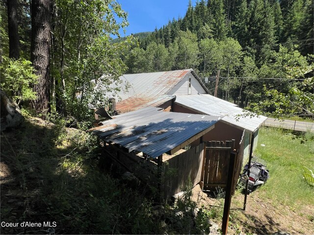 view of property exterior with metal roof and a view of trees