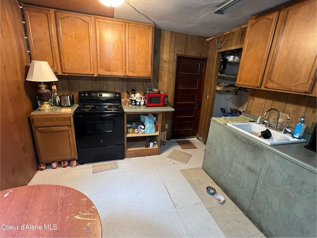 kitchen with black appliances, wood walls, and sink