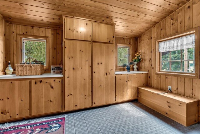 interior space with vaulted ceiling, light tile patterned flooring, wooden ceiling, and wooden walls