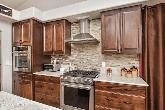 kitchen with stainless steel appliances, wall chimney range hood, and decorative backsplash