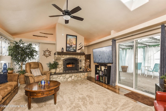 living area featuring lofted ceiling with skylight, a fireplace, ceiling fan, and wood finished floors