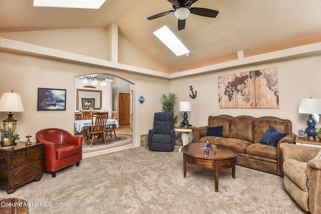 living room featuring a skylight, a ceiling fan, arched walkways, and carpet flooring