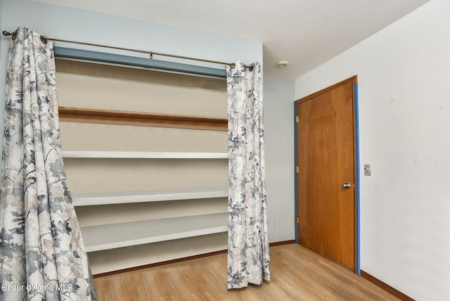 interior space with baseboards and wood finished floors