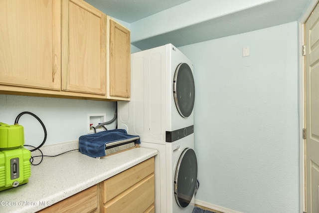 laundry area with stacked washer / dryer, cabinet space, and baseboards