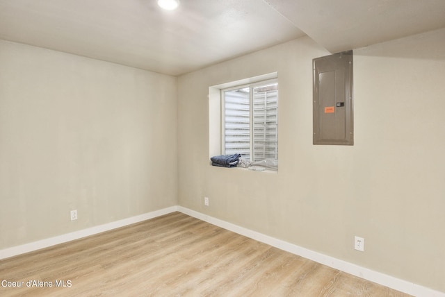 spare room with electric panel, baseboards, and wood finished floors