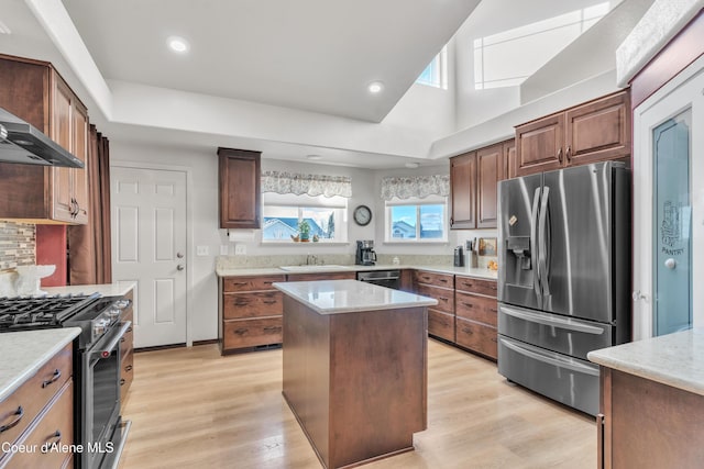 kitchen with appliances with stainless steel finishes, backsplash, a kitchen island, and light wood-style flooring