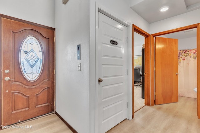 foyer featuring light wood finished floors, baseboards, and visible vents