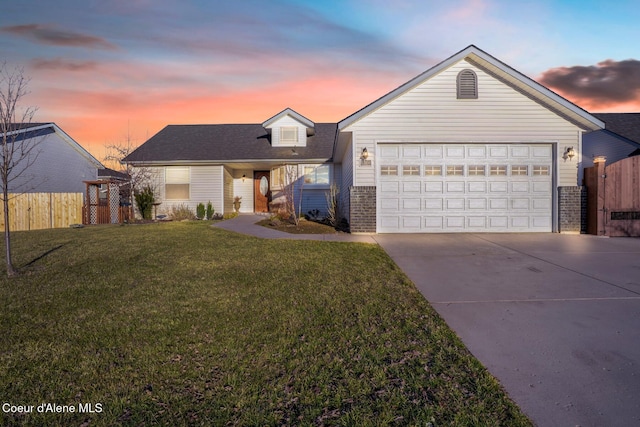 view of front of home with driveway, fence, a lawn, and brick siding