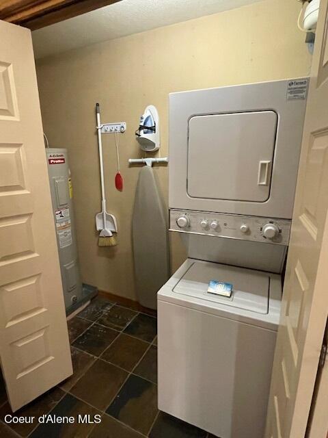 clothes washing area with water heater and stacked washer and clothes dryer