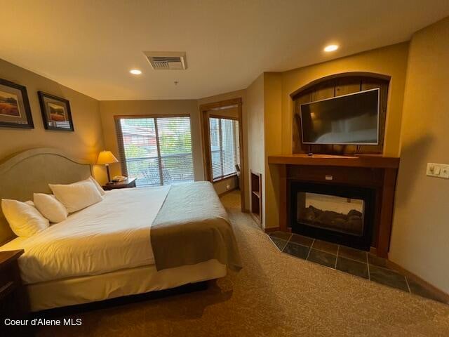 carpeted bedroom featuring a tile fireplace and access to outside