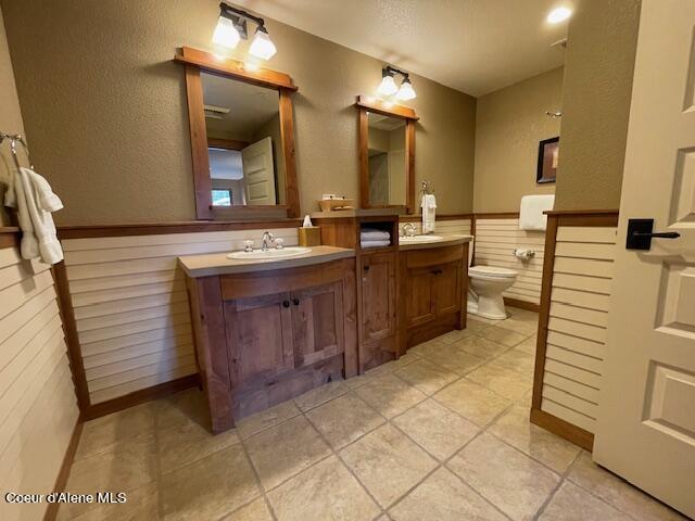 110 Morning Star Dr Unit 237, Kellogg, ID 83837 - full bathroom featuring a wainscoted wall, wood walls, vanity, and toilet