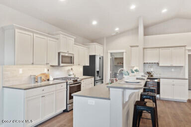 kitchen with stainless steel appliances, white cabinets, and a center island with sink