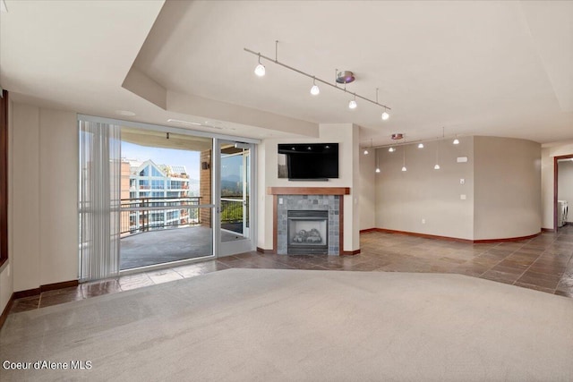 unfurnished living room featuring track lighting, baseboards, a tiled fireplace, and carpet flooring