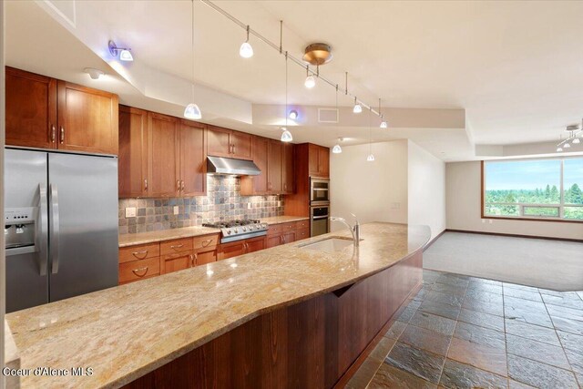 kitchen featuring stainless steel appliances, decorative backsplash, light stone counters, dark carpet, and track lighting