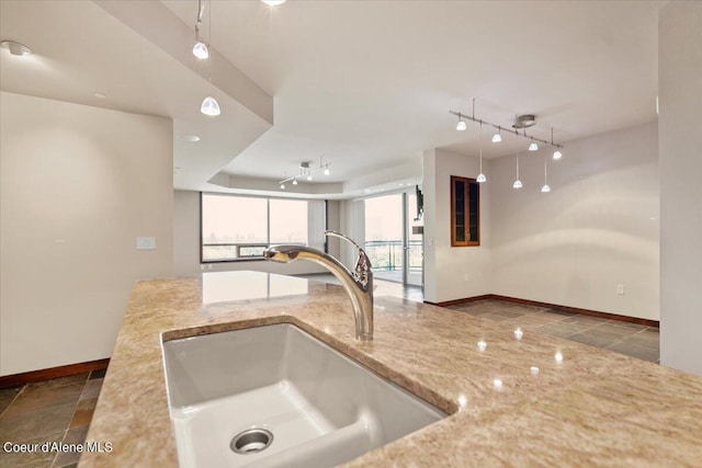 kitchen with baseboards, a sink, and track lighting