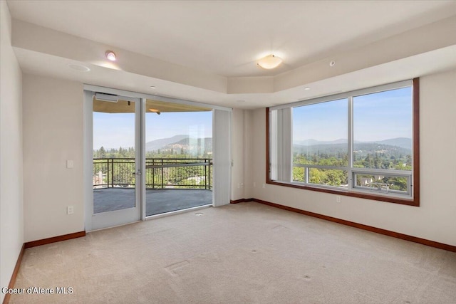 unfurnished room with baseboards, a mountain view, and a wealth of natural light