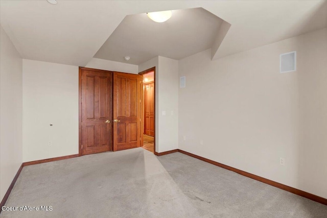 unfurnished bedroom with light colored carpet, a closet, visible vents, and baseboards