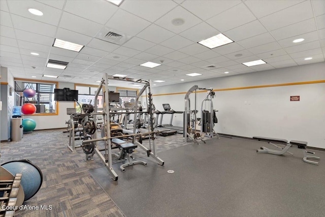 workout area featuring visible vents, a drop ceiling, and baseboards