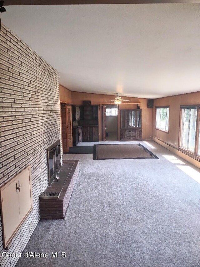 unfurnished living room with ceiling fan, dark carpet, and a fireplace