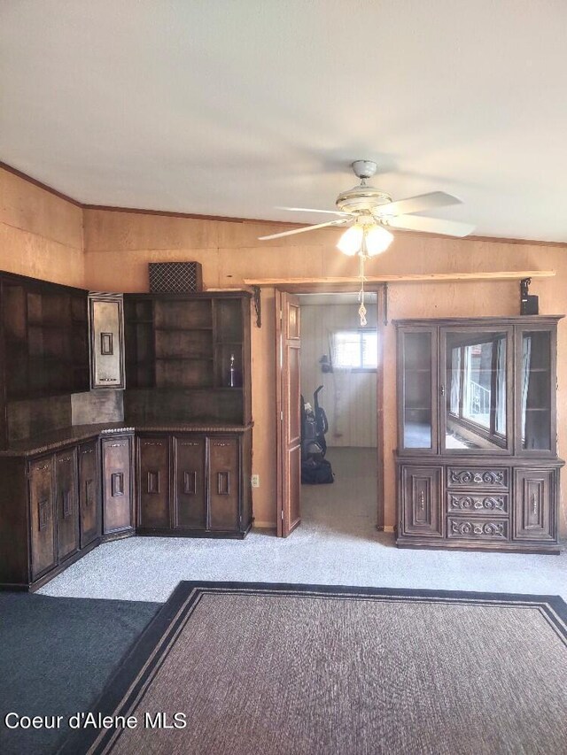 interior space with lofted ceiling, light colored carpet, ceiling fan, and wood walls