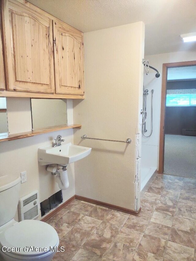 bathroom featuring walk in shower, toilet, and a textured ceiling