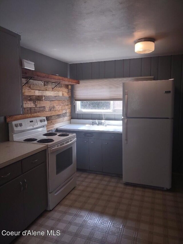 kitchen featuring sink, white appliances, and wood walls