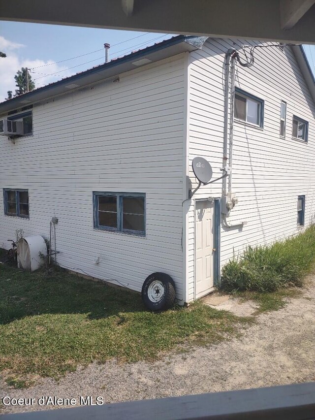 view of home's exterior featuring a lawn and a wall unit AC