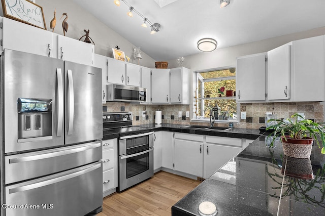 kitchen with stainless steel appliances, tasteful backsplash, sink, white cabinetry, and light hardwood / wood-style flooring