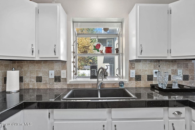 kitchen featuring tasteful backsplash, white cabinets, and sink