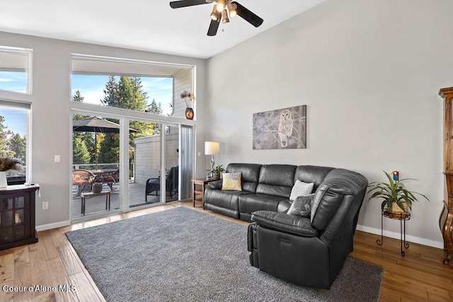 living room with a high ceiling, ceiling fan, and hardwood / wood-style floors