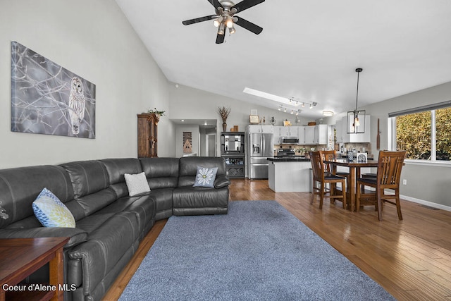 living room with ceiling fan, dark hardwood / wood-style floors, and vaulted ceiling