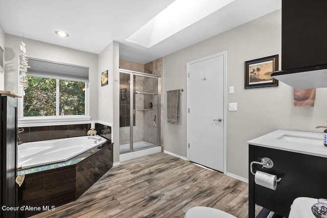 bathroom featuring wood-type flooring, a skylight, vanity, and independent shower and bath