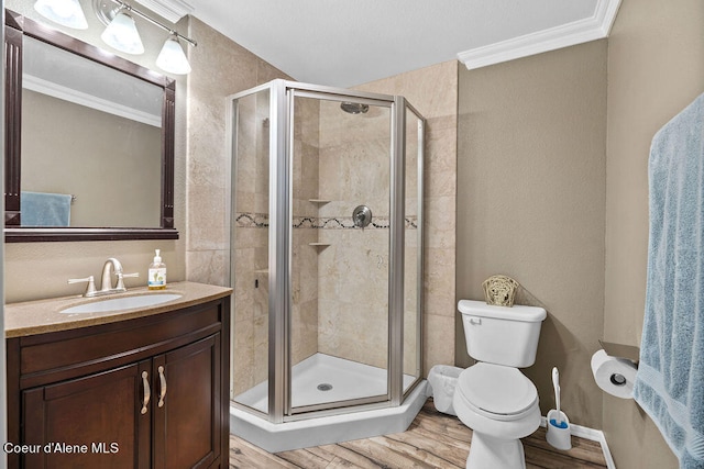 bathroom featuring toilet, crown molding, an enclosed shower, hardwood / wood-style flooring, and vanity