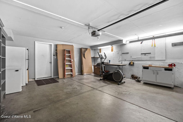 garage featuring a garage door opener, white fridge, and a workshop area