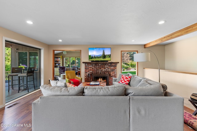 living room with beam ceiling, a fireplace, and hardwood / wood-style floors