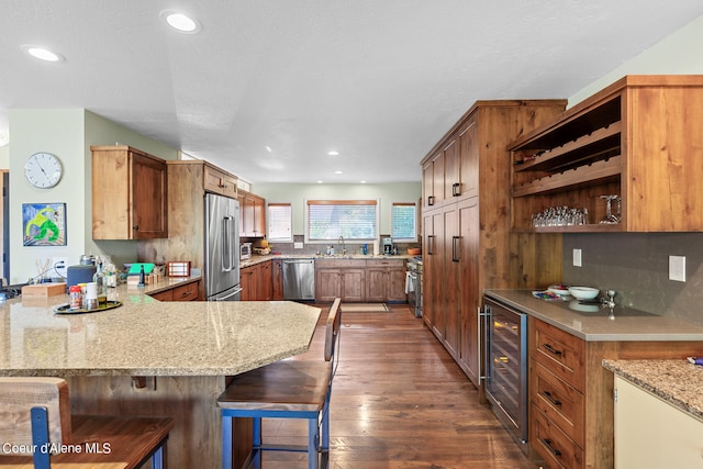 kitchen with premium appliances, a breakfast bar area, wine cooler, kitchen peninsula, and dark wood-type flooring