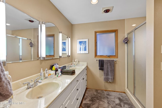 bathroom with dual vanity and a shower with shower door