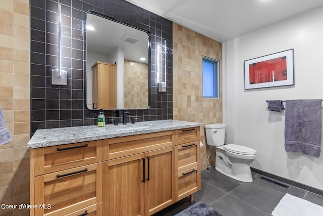 bathroom featuring tasteful backsplash, toilet, vanity, tile walls, and tile patterned floors