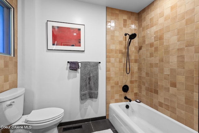 bathroom featuring tiled shower / bath combo, toilet, and tile patterned floors