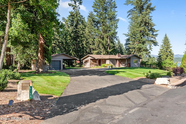 9740 N Easy St, Hayden Lake, ID 83835 - ranch-style house with a front lawn, a carport, driveway, an outdoor structure, and a chimney