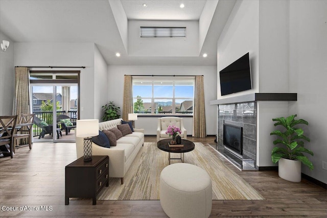 living room featuring a fireplace, wood-type flooring, and a high ceiling