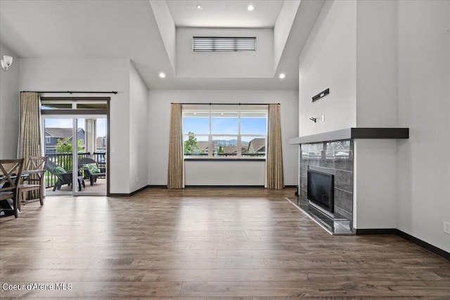 unfurnished living room featuring a fireplace, dark hardwood / wood-style flooring, and a towering ceiling