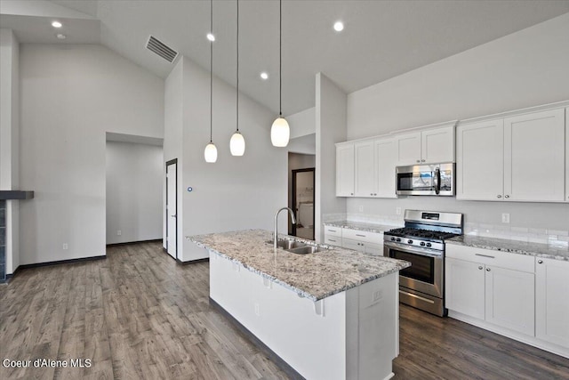 kitchen with pendant lighting, appliances with stainless steel finishes, a kitchen island with sink, and white cabinets