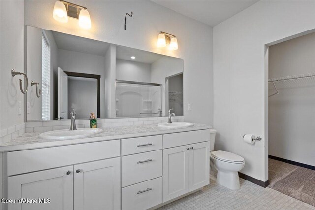 bathroom with a shower with door, vanity, and toilet