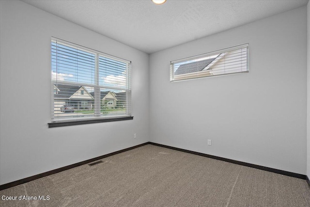 carpeted empty room with a textured ceiling